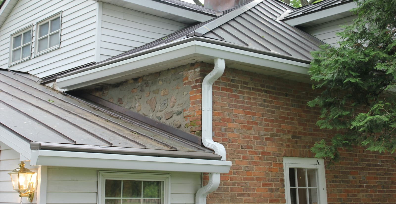 Gutter Installation in Troy on a brick house with metal roofs. Do gutter guards increase home value?