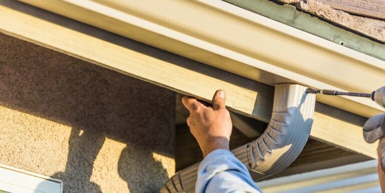 New gutters being installed after a replacement covered by homeowners insurance.
