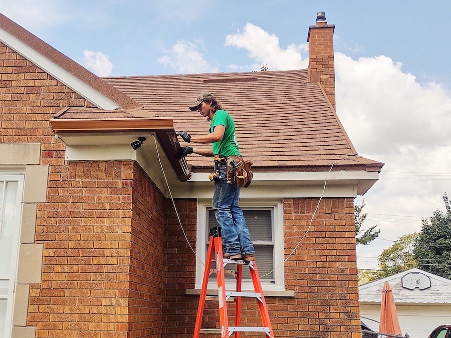Homeowner inspecting gutter guards on a residential roof to ensure proper drainage and debris protection